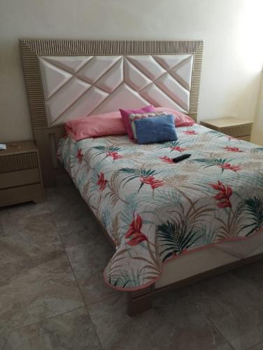ein Schlafzimmer mit einem Bett mit einer Blumendecke und Kissen in der Unterkunft Apartamentos sammtours in Valledupar