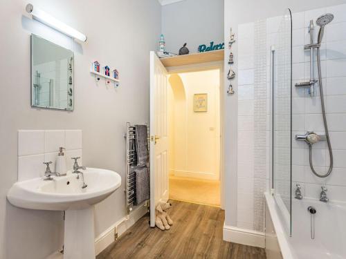 a white bathroom with a sink and a shower at Admirals Rest in Cromer