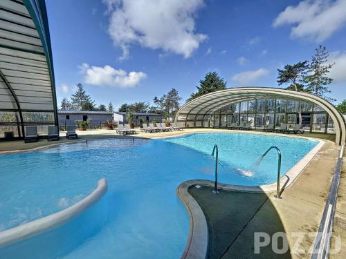 une grande piscine devant un immeuble dans l'établissement Chalet cozy à Jullouville - 4 pers, piscine chauffée, proche plage et commerces - FR-1-361-538, à Jullouville