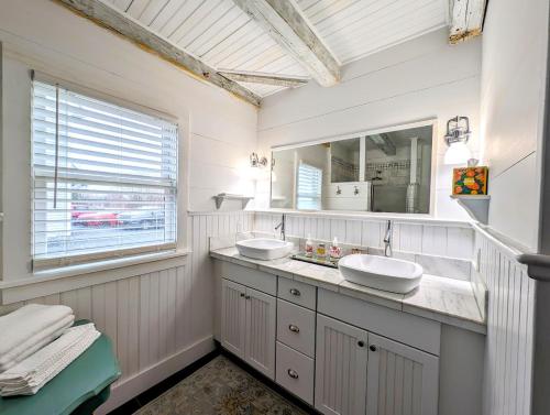 Baño blanco con 2 lavabos y ventana en Oceanside Saltwater Cottage NEW, en Milbridge