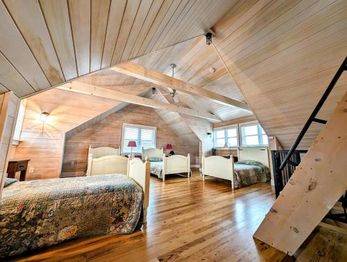 un dormitorio en el ático con 2 camas y una escalera en Oceanside Saltwater Farm House NEW, en Milbridge