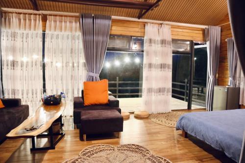 a bedroom with a bed and a chair and a window at JE T'AIME VILLA - Khu nghỉ dưỡng nhà vườn nằm giữa thiên nhiên bao la hoa cỏ in Bao Loc