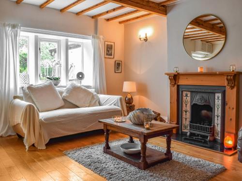 a living room with a white couch and a fireplace at Lavender Cottage in Kirkburton