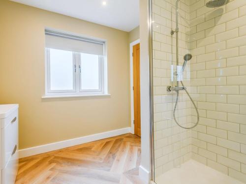 a bathroom with a shower with a glass door at Cherry Ridge in Great Bircham