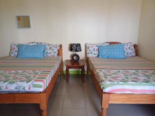 een kamer met 2 bedden en een bijzettafel bij Calitang Pearl Cottage in Nacpan