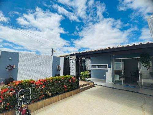 a blue house with a patio and flowers at Casa Aconchegante com Piscina in Petrolina