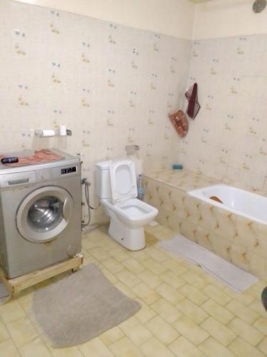 a bathroom with a toilet and a tub and a washing machine at F1 Cosy in Dakar