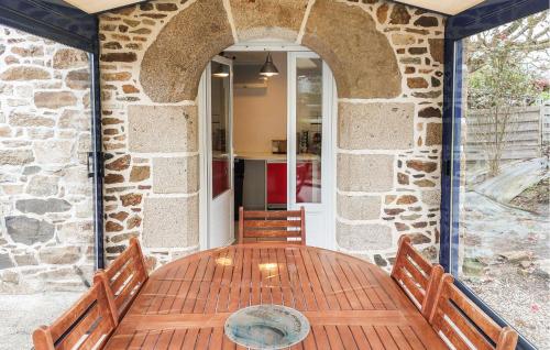 une table en bois avec des bancs et un mur en pierre dans l'établissement 2 Bedroom Cozy Home In Plouha, à Plouha