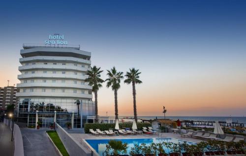 un hotel con una piscina, palmeras y el océano en Sea Lion Hotel en Montesilvano