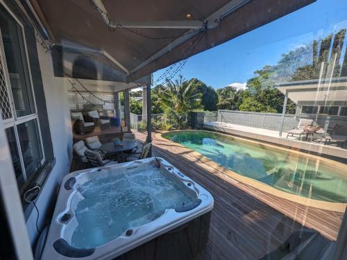 a bath tub on a deck next to a swimming pool at Phoenix Oasis, Family and Pet friendly, with private pool and spa in Port Macquarie