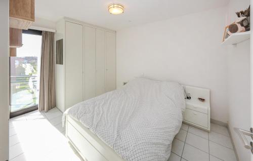 een witte slaapkamer met een bed en een raam bij Lovely Apartment In Oostende With Kitchen in Oostende
