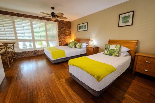a bedroom with two beds and a table in it at Ballina Palms Boutique Motel in Ballina