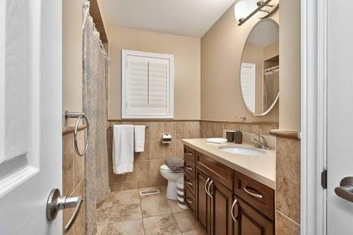 uma casa de banho com um WC, um lavatório e um espelho. em 4 Car Parking-King Bed-in Oakville, with Ping Pong-BBQ, highway access em Oakville