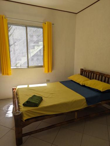 a bedroom with a bed with yellow sheets and a window at Green House Boracay in Boracay