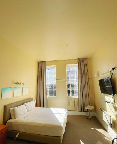 a hotel room with a bed and two windows at Grand Central Serviced Apartments in Auckland