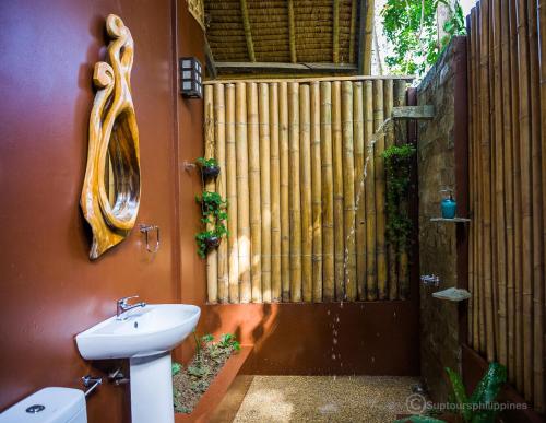 a bathroom with a toilet and a sink at Fox & The Firefly Cottages in Loboc