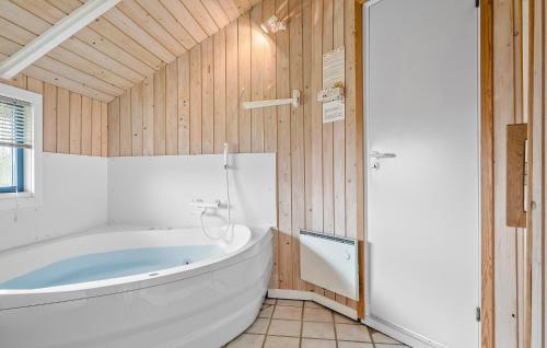 baño con bañera blanca grande y paredes de madera. en Beautiful Home In Sydals With Kitchen, en Sønderby