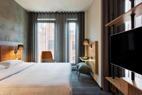 ein Hotelzimmer mit einem Bett und einem Flachbild-TV in der Unterkunft Moxy Warsaw Praga in Warschau