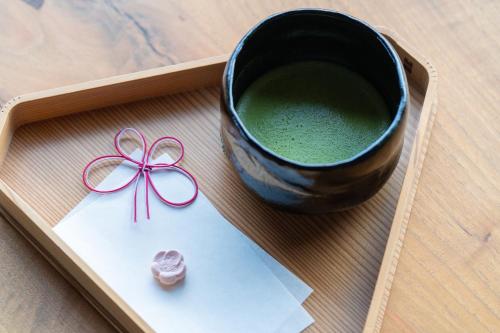 a cup of green liquid with a pink bow next to a paper at NISEKO Inn of Youtei Raku Suisan in Kutchan