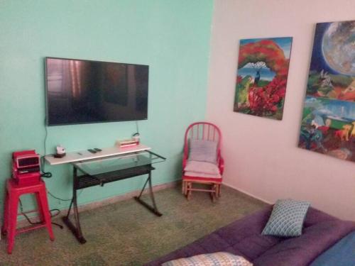 a living room with a desk and a tv on the wall at Porta del Sol ~Less than 1 m to center of town! in San Germán