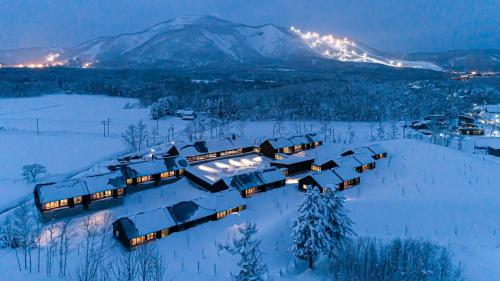a house in the snow with a mountain in the background at NISEKO Inn of Youtei Raku Suisan in Kutchan