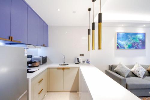 a kitchen with white counters and blue cabinets at Changsha Zealandia Serviced Apartment in Changsha