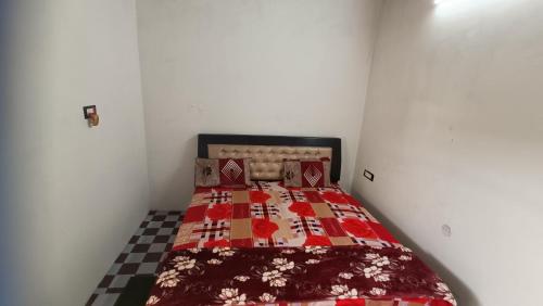 a small bedroom with a bed with a red quilt at Keshav Narayan Home Stay in Mathura