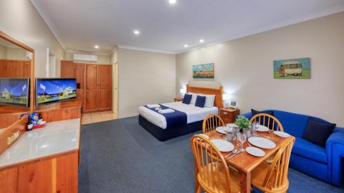 a hotel room with a king sized bed and a living room at Breakout Motor Inn in Cowra