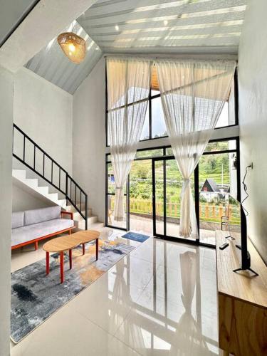 a living room with a bench and large windows at Go Dieng Cabin 4 in Dieng