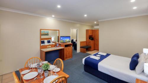a hotel room with a bed and a dining room at Breakout Motor Inn in Cowra