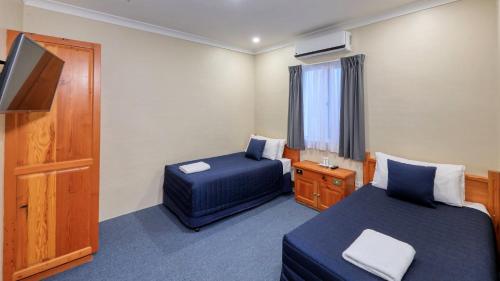 a hotel room with two beds and a television at Breakout Motor Inn in Cowra