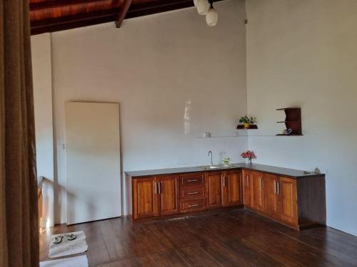 an empty kitchen with a sink and wooden cabinets at Serenity Stay in Badulla