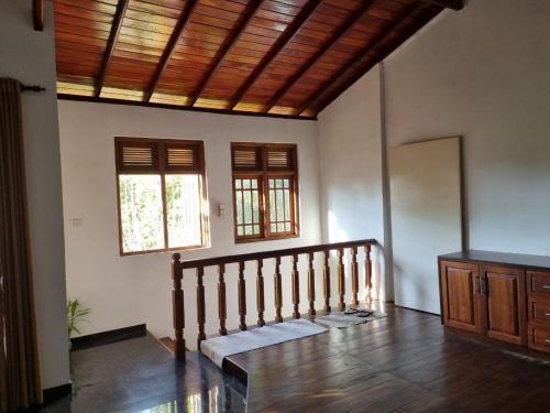 a living room with a wooden ceiling and a staircase at Serenity Stay in Badulla