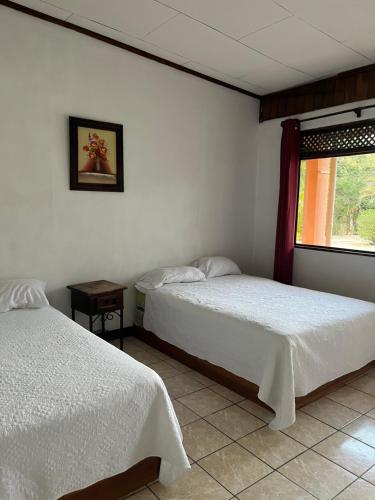 1 dormitorio con 2 camas y ventana en Hotel Nacaome Blue Zone, en Tapantí