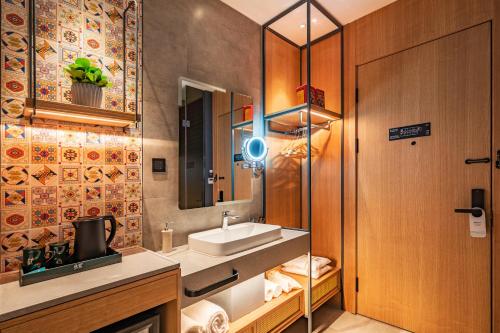 uma casa de banho com um lavatório e um espelho em Qiuguo Hotel - Beijing Chaoyang Branch em Pequim