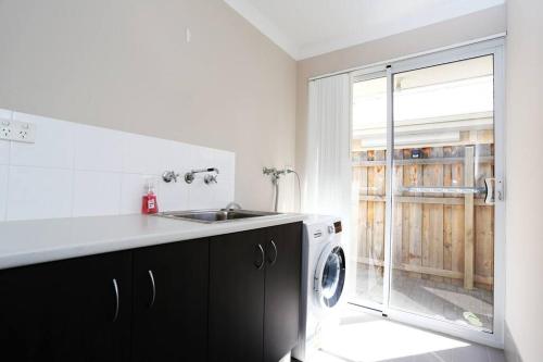 a kitchen with a sink and a washing machine at Nice and Neat House for your Journey - Renovated in Perth