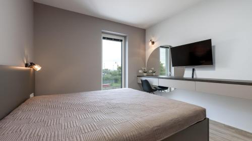 een slaapkamer met een bed, een bureau en een televisie bij AV apart hotel in Senec