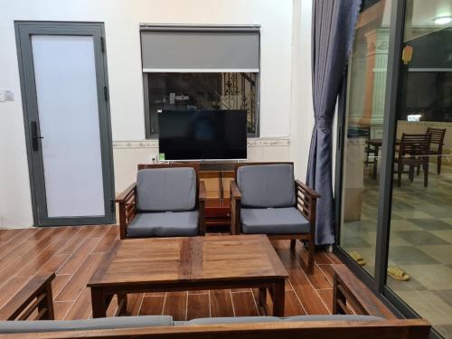 a living room with two chairs and a table and a tv at RUBY HOTEL Vĩnh Long in Vĩnh Long