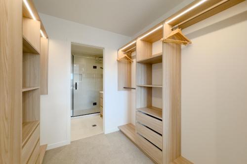 a walk in closet with wooden shelves and a shower at Spacious Townhouse in Epsom School Zone in Auckland