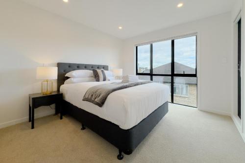 a white bedroom with a large bed and a large window at Spacious Townhouse in Epsom School Zone in Auckland