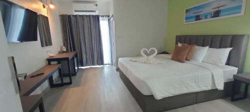 um quarto com uma cama branca e uma televisão em Remas Hotel Hatyai em Hat Yai