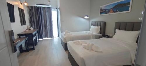 a hotel room with two beds and a window at Remas Hotel Hatyai in Hat Yai