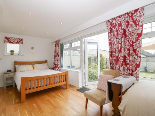 a bedroom with a bed and a chair and a window at Gables Retreat in Trearddur