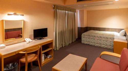 a hotel room with a bed and a desk with a television at Tabist Hirosaki Touei Hotel in Hirosaki