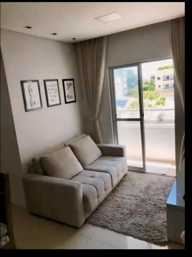 a living room with a couch and a large window at Apartamento bem localizado em fortaleza in Fortaleza