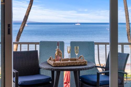 a table and chairs on a balcony with a view of the ocean at Nani Kai Hale 209- Remodeled prime oceanfront 1 bedroom Kihei gem in Kihei