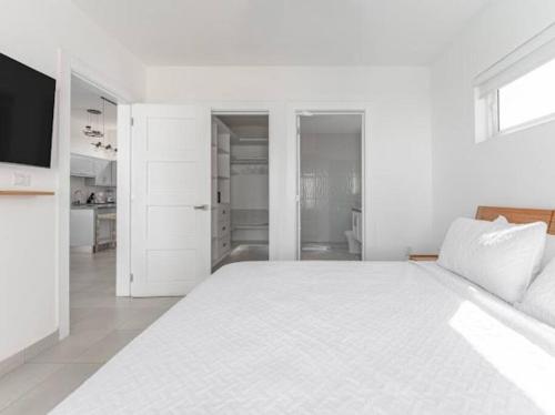 a white bedroom with a large bed and a kitchen at Caribbean Paradise Villa - 3 bed, 3 Bath and Pool in Sosúa