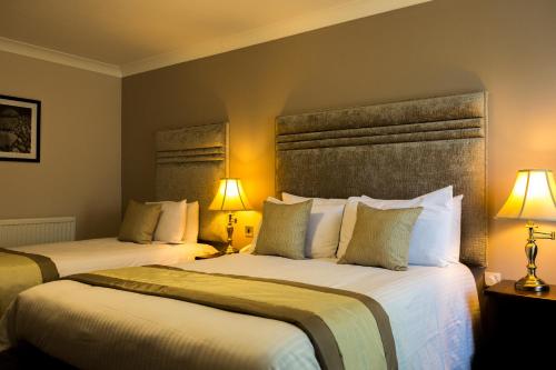 two beds in a hotel room with two lamps at Best Western Plus West Retford Hotel in Retford