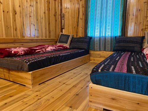 two beds in a room with wooden walls and wooden floors at Dung & Sang House in Sapa