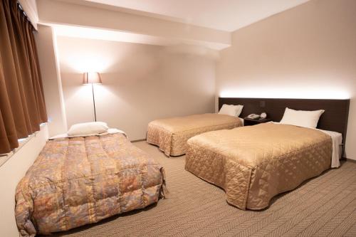 a hotel room with two beds and a lamp at Hotel Aisul Matsuyama in Matsuyama
